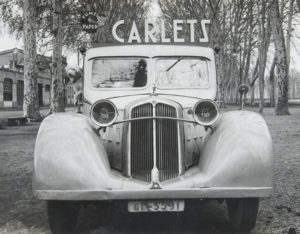 Vista frontal d'un vehicle Renault amb publicitat de la fàbrica Paper Carlets, d'Olot, al passeig de la Devesa, a Girona.