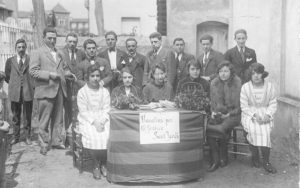 Comissió organitzadora de la diada de Sant Jordi en una parada de clavells davant del convent dels caputxins. ACGAX. Servei d'Imatges. Col·lecció d'imatges de Josep M. Dou Camps. Autor desconegut, 1921.