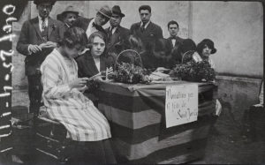Comissió organitzadora de la diada de Sant Jordi en una parada de clavells davant del convent dels caputxins. ACGAX. Servei d'Imatges. Fons Josep M. Melció Pujol. Autor desconegut, 1921.