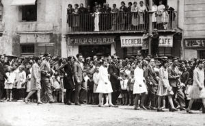 Vista parcial del passant de les parelles participants a la sardana de Corpus, a la plaça Major. ACGAX. Servei d'Imatges. Col·lecció L'Abans. Cessió d'Anna Montañá Gratacós. Autor: Emeteri Vélez Valls, 1928.